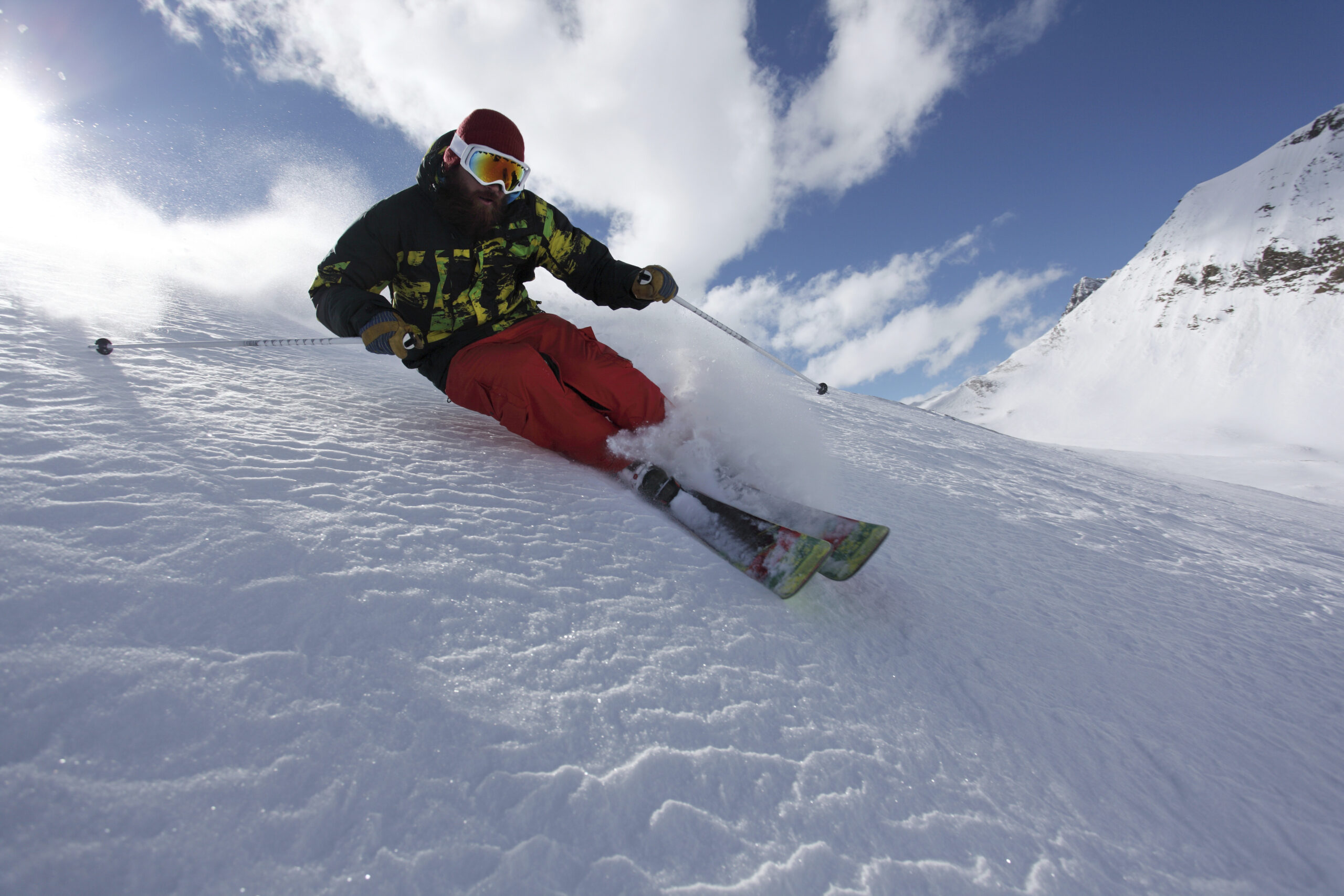 Skier carving through fresh powder on a sunny mountain slope